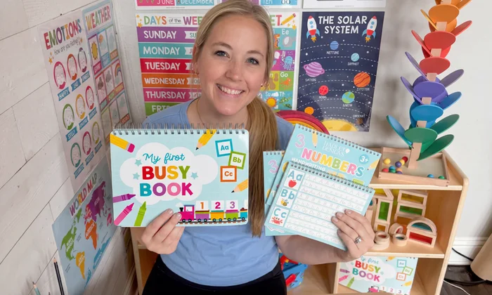 Becca holding the My First Busy Book and Numbers kit in her classroom